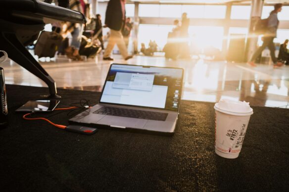 A laptop in an airport with a coffee next to it.