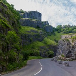 A road winds through a lush green stretch of Cheddar Gorge, England