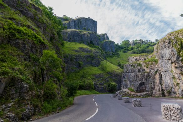 A road winds through a lush green stretch of Cheddar Gorge, England