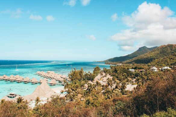 Overwater bungalows over turquoise water along forested mountains in Moorea, French Polynesia