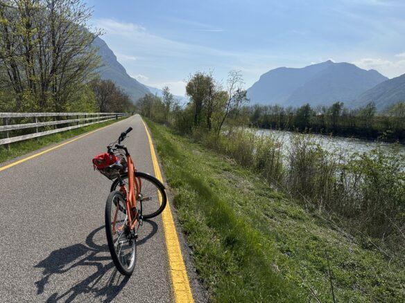 A bicycle path along the Adige River and Dolomitic Alps mountains in the Trentino region of Italy.