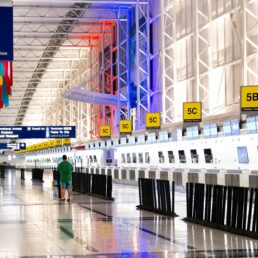 check-in kiosks in an airport terminal with just a few passengers.