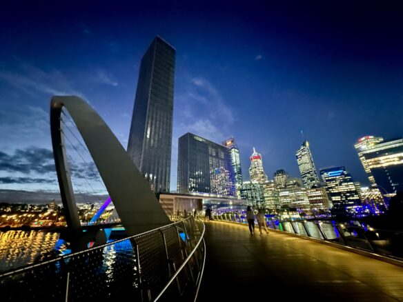 A few people walking over a pedestrian bridge along Elizabeth Quay in Perth, Australia.