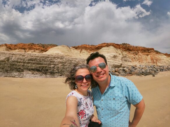 Alex and Bell on the Port Noarlunga, South Australia beach with colorful red and cream hued cliffs in the backdrop