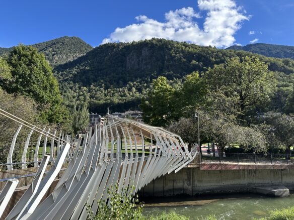 A pedestrian bridge over the Gran Valira with forested mountains towering over Andorra La Vella