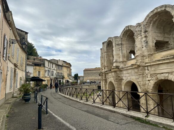 A cloudy sky over Arles, including the Roman built amphitheatre of Arles Arena and nearby pastel colored buildings. 