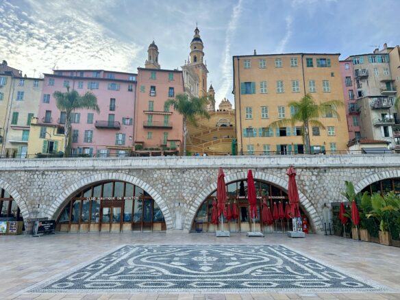 Pastel colored buildings and a zigzag staircase up to a cathedral in Menton, France.