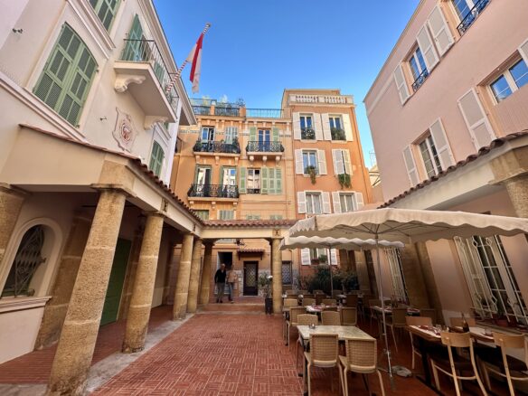 An empty terrace with a pastel colored orange building in Monaco City, Monaco