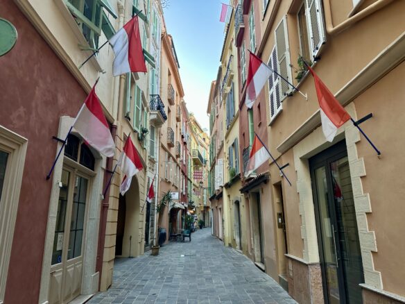 A pedestrian only laneway in Monaco City lined with the official red and white flags of the nation. 