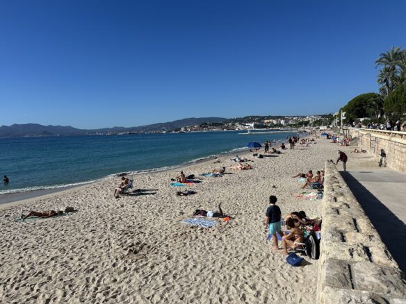 People laying out on the beach in Cannes France with a perfect blue sky above